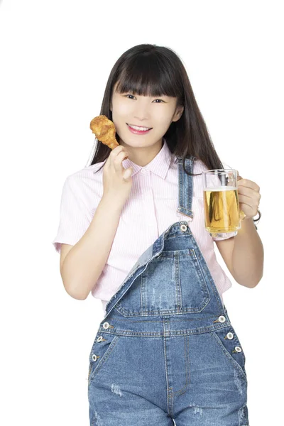 フライド チキンのドラムスティック 白い背景で隔離のビールのマグカップを食べる中国アメリカ美人 — ストック写真