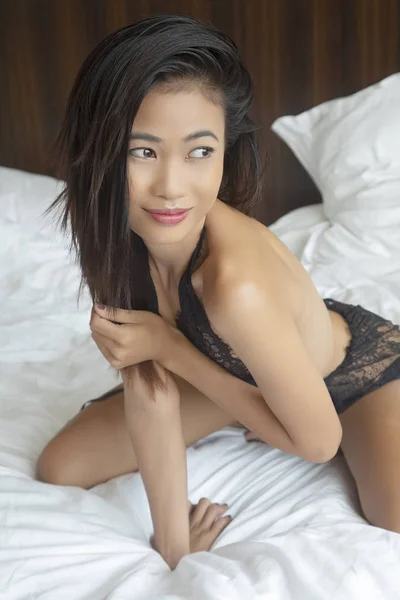 美しいアジアの女性の白いシーツでベッドの上で黒のランジェリーを着てポーズ — ストック写真