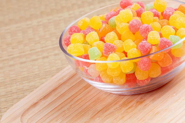 Fruit gum drops in glass bowl on a wooden background