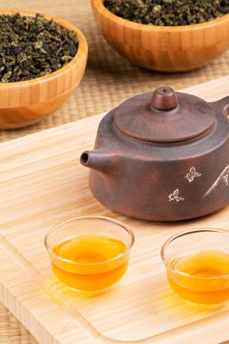 Geleneksel Çin çay demliğine ve ahşap arka planda izole edilmiş yeşil çaya yakın.