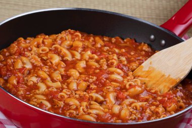 Lezzetli gulaş ve noddles kırmızı tavada ahşap spatula ile