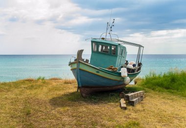 Eski kırık tekne terk edilmiş yerde akuamarin deniz yakınında yerde kalır
