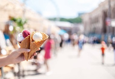 Beyaz ve macenta buz ile iki waffle konileri tutan kadın eli