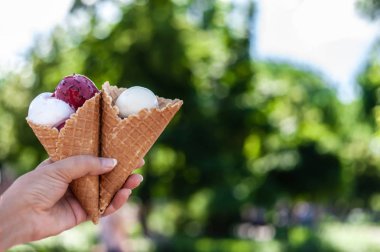 Beyaz ve macenta buz ile iki waffle konileri tutan kadın eli
