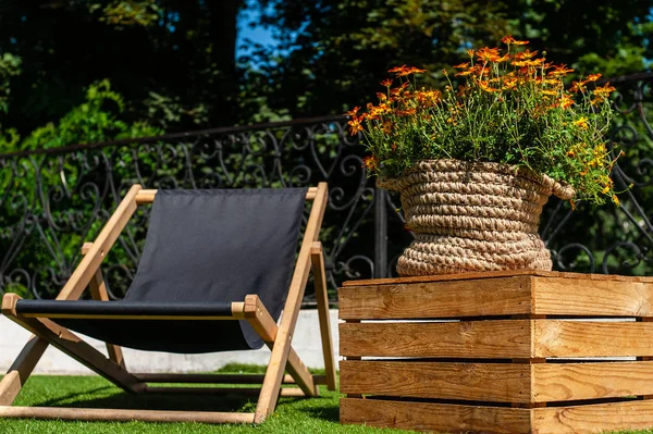 Ein Liegestuhl und ein Blumenstrauß in gestricktem Jutetopf auf der Veranda — Stockfoto