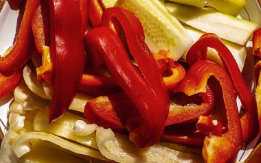 bir tabakta sarı ve kırmızı biber dilimlenmiş parçalar