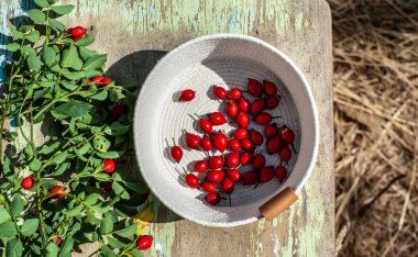 Eski renkli ahşap yüzeyüzerinde beyaz sepet kırmızı meyveleri. Yap