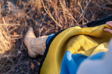 Renkli battaniyeye sarılmış deri kovboy çizmeli bayan bacağı 