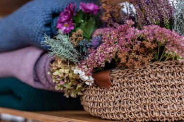 Kırsal örgü sepetinin yanında bir yığın sıcak renkli battaniye.