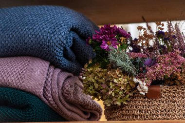 Kırsal örgü sepetinin yanında bir yığın sıcak renkli battaniye.