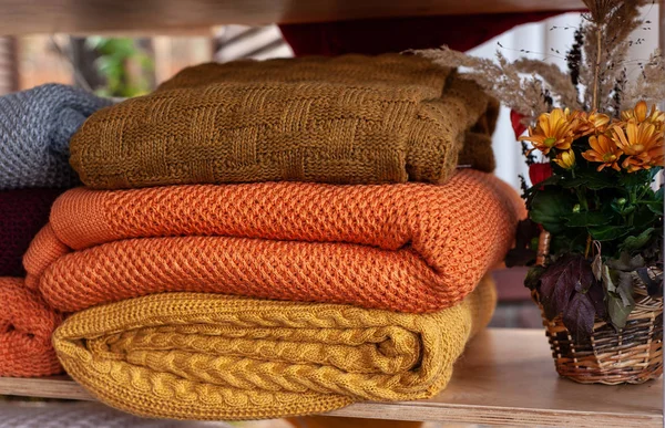 A pile of warm colorful blankets near rustic knitted basket with — Stock Photo, Image