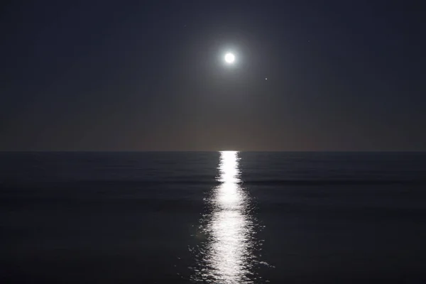 La gran luna llena se eleva sobre el mar por la noche. Luz lunar reflejada en el agua. Camino lunar. Océano . —  Fotos de Stock