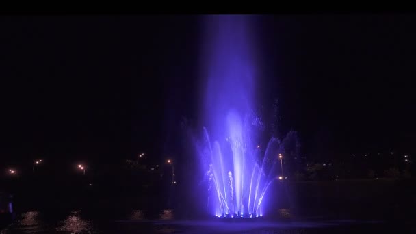 Fontaine dansante colorée la nuit sur fond sombre . — Video