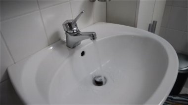 Modern krom musluk veya beyaz lavabo içine akan su ile dokunun