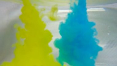 Mavi ve sarı mürekkep suda karışıyor. Sualtı yavaş çekim yakın.