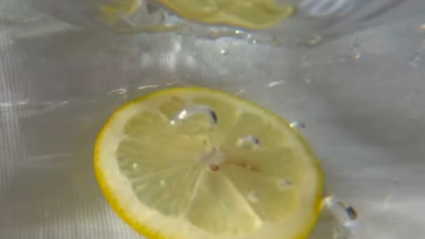 Круглий шматочок лимона занурюється у воду. Підводний високошвидкісний повільний рух — стокове відео