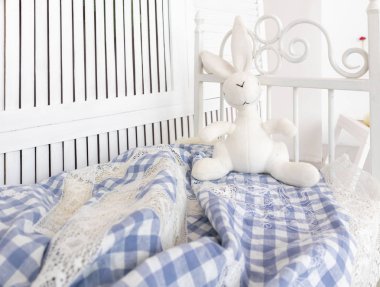 Parlak beyaz çocuk odası, yatağı ve oyuncağı var.