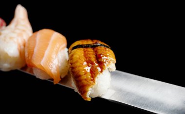 Japon dürümleri ve deniz ürünleri suşisi. Siyah arka planda katana kılıcı.