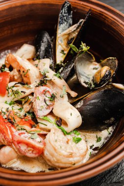 Kara tahtada siyah bir tabakta deniz ürünleri midye ve peynirli makarna.