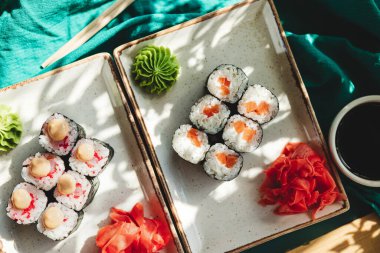 Masanın üstünde deniz mahsulleri olan suşi ruloları.