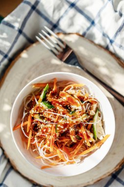 Sebzeli pirinç eriştesi ve tavuklu yuvarlak tabak. Kafede güneş ışığı.