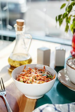 Sebzeli pirinç eriştesi ve tavuklu yuvarlak tabak. Kafede güneş ışığı.