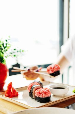 Kızın elinde çubuklar ve suşi ve deniz ürünleri taze balık ve yılan balığı var.