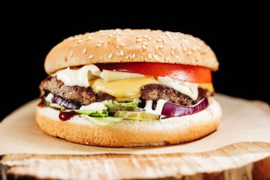 Tahtadaki hamburgerin üzerinde siyah bir parşömen var.