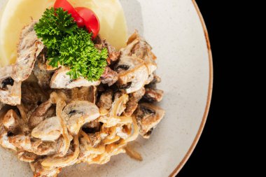 Krema soslu mantarlı patates püresi ve koyu arkaplanda domates.