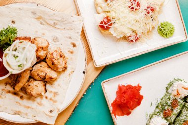 Peynirli şiş tavuk kebabı ve makarnalı domatesli suşi tabağın üstünde rulo suşi.