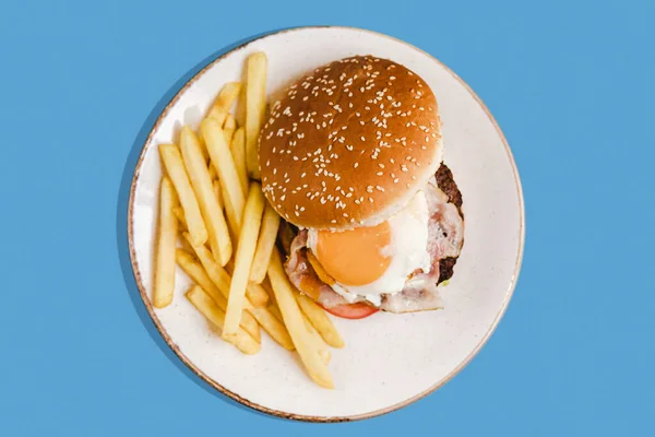 Hamburger Masovou Kotletou Kuřecím Vejcem Talíři Hranolky Modrém Pozadí — Stock fotografie