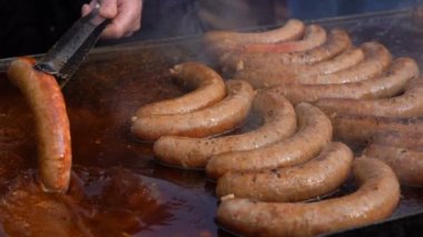 Sokak gıda büyük kızartma tavası açık yemek. Lezzetli sosis büyük ticari zor durumda aspiratör - yavaş hareket üzerinde. Yemek ve Sausages.Tongs elinde tutan sosis satan sokak gıda Pazar satıcıları.