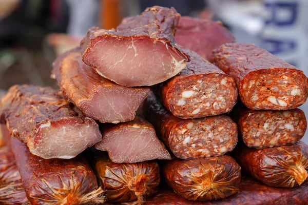 Selling Smoked Meat at Street Market. Food stand with cold smoked meat with prosciutto and salami. Pile of smoked meat.