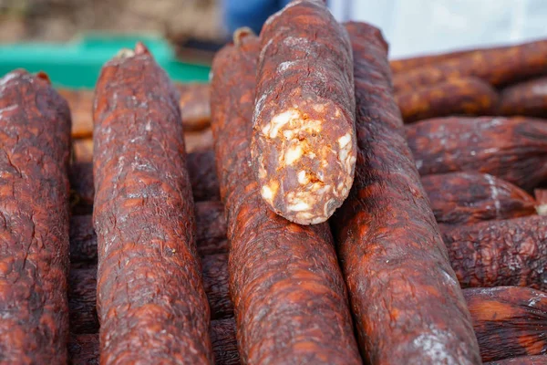 Selling Smoked Sausages at Street Market. Food stand with cold smoked meat. Pile of smoked sausages.