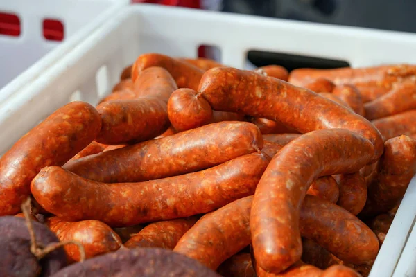Delicious Sausages Exposed for Sale in the Market. Food stand fresh sausages. Pile of spicy sausages in plastic crate.