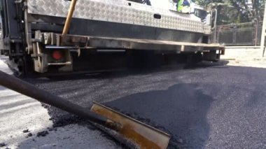 Asfalt yol inşaat alanında - yavaş hareket makine döşeme. Taze asfalt bir yol inşaat sitesinde tesviye işçisi.
