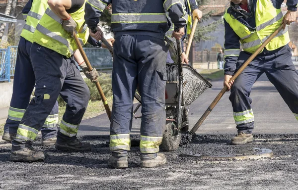 Trabajadores de la construcción de carreteras nivelando asfalto - Trabajo en equipo — Foto de Stock