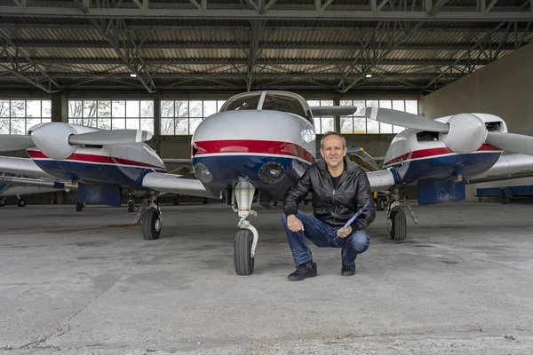 Smiling Pilot in front of Modern Private Airplane in a Hangar