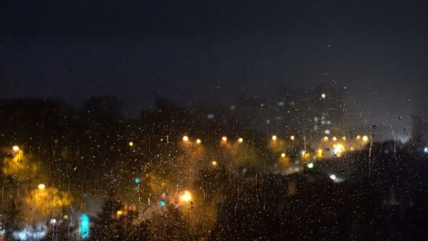 透过家庭窗与雨滴的模糊城市夜照明视图 城市通过雨窗口 雷雨期间玻璃窗对夜城街的雨滴 — 图库视频影像