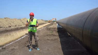 Gaz Boru Hattı Şantiyesinde Radyo İletişim Cihazı Üzerinden Konuşan Mühendis. Boru hattı yapım aşamasında. Mühendis Kontrol Petrokimya Petrol / Gaz Boru Hattı.