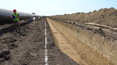 Gaz Boru Hattı Şantiyesi. Borular destekleyici kum torbaları üzerine serilir, birlikte kaynaklı ve eoksi ile kaplanmış kaynak eklemleri.
