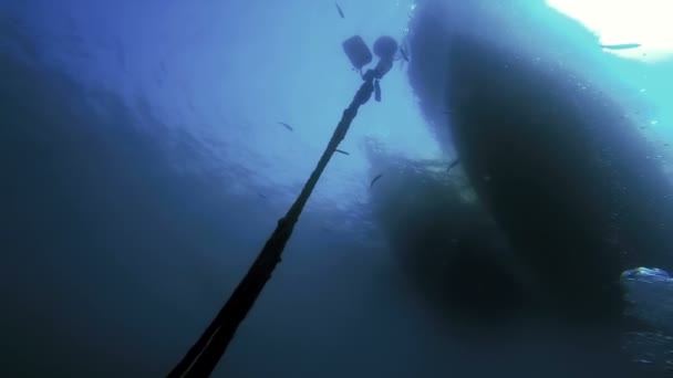 水肺潜水员在慢动作中坠入蓝水中 水下景观透过清澈的蓝色海水仰望船体底部 潜水船后面的阳光爆裂 — 图库视频影像