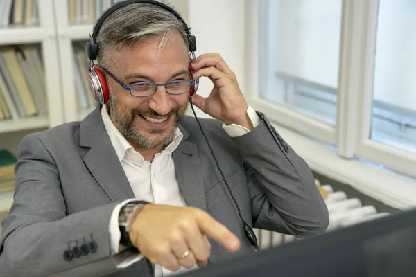 Happy Man With Headphones Looking at Computer Monitor