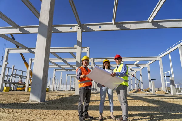 Group of Business People in Yellow and Red Hardhats Discuss a Project on Site Under Construction — Stock Photo, Image