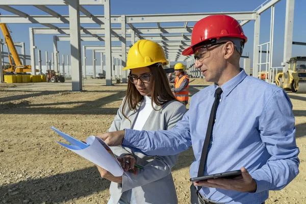 Jonge vrouwelijke architect en zakenman met digitale tablet vergadering op bouwplaats — Stockfoto