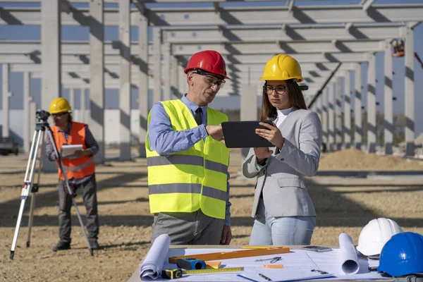 Junge Architektin mit digitalem Tablet und reifer Geschäftsfrau treffen sich auf Baustelle — Stockfoto