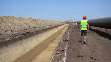 İnşaat Ustası Boru Hattı İnşaat Alanında İlerleme Kontrol Ediyor. Red Hard Hat ve Sarı Batı Yakıt Boru Hattı 'nın yanında yürüyen işçi. Türk Akımı Boru Hattı İnşaatı.