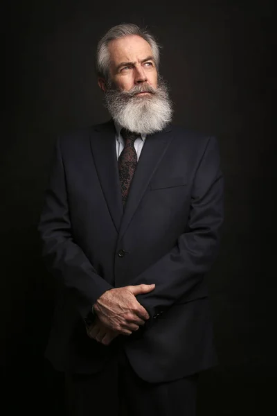 暗い背景にスーツを着て白髪と完全なひげ 年配の男性のクローズ アップ — ストック写真