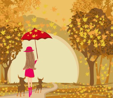 Zarif bir kadın bir sonbahar günü köpeklerini gezdirir.