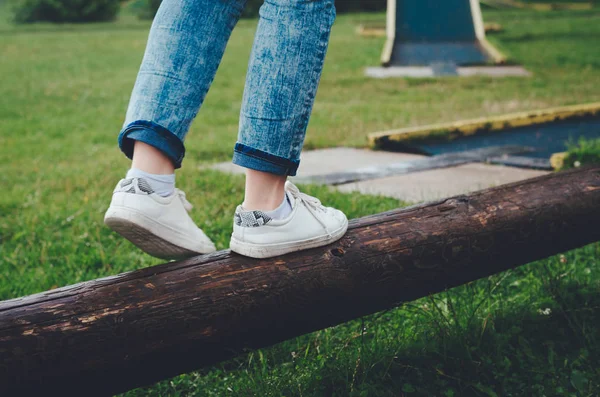 低部分的女孩平衡在一个白色帆布鞋的日志 — 图库照片
